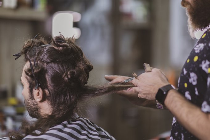 Fryzjer układa męską fryzurę z długich włosów